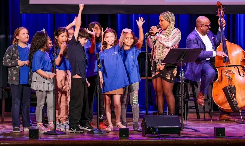 Students performing onstage with a singer and upright bassist during a School Engagement in the Arts event